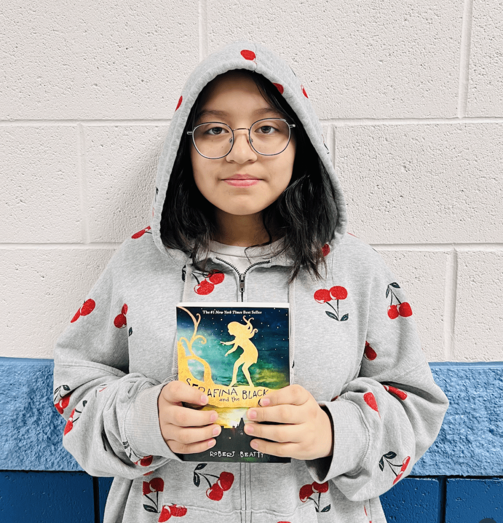 student holding a book received for earning a  praise award